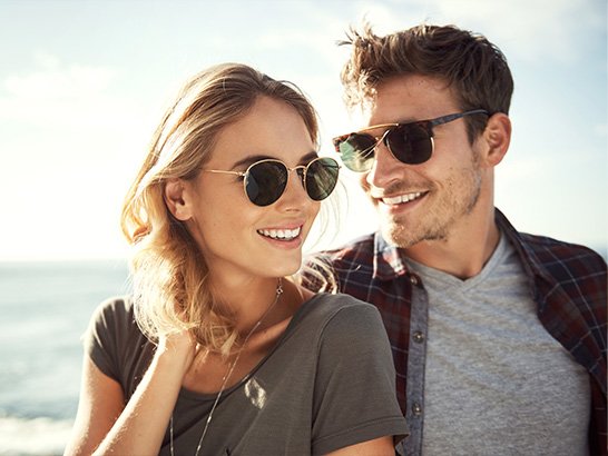 deux personnes souriantes au soleil portant des lunettes solaires
